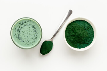 Spirulina algae powder in bowl and cold milk latte drink, top view