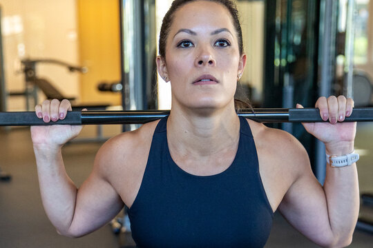 Strong, muscular woman lifting weights in gym during workout. Competitive female weightlifter