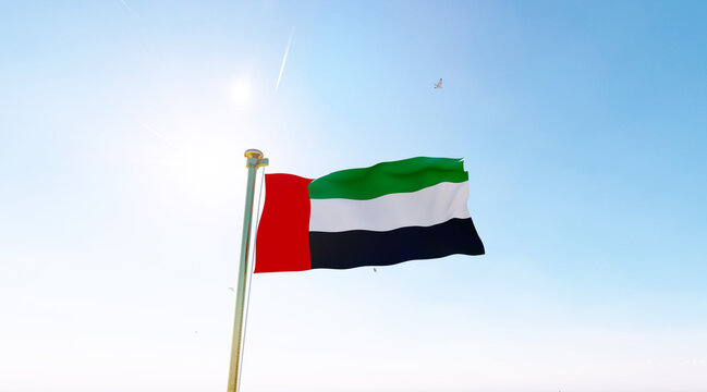 Flag of United Arab Emirates flag waving in the wind, sky and sun background. United Arab Emirates Flag.