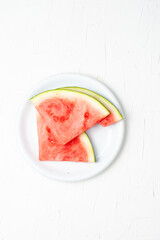 Overhead view of red watermelon slices on plate and white background, vertical, with copy space