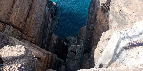 This image shows a dramatic cliffside overlooking the ocean. The cliff is covered in lush vegetation, and the ocean is a deep blue color. The image captures the beauty and power of nature.