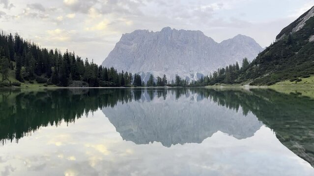 Mountain Zugspritze is reflected on lake Seebensee sky light overcast