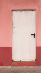 Puerta industrial blanca en pared rosa y roja