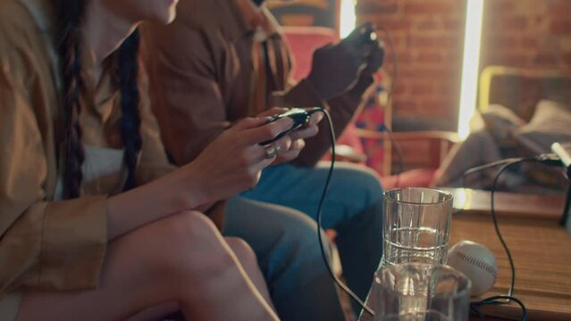 Unrecognizable young woman and her boyfriend having fun playing retro console game, 90s aesthetics