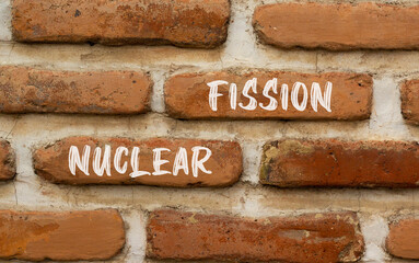 Nuclear fission symbol. Concept words Nuclear fission on beautiful brick wall. Beautiful red brown...