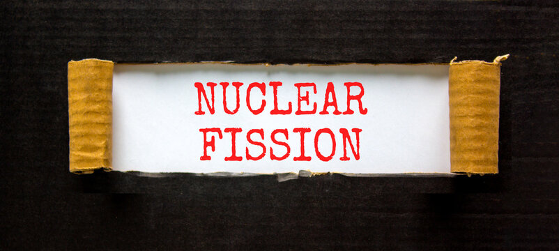 Nuclear fission symbol. Concept words Nuclear fission on beautiful white paper. Beautiful black paper background. Business science nuclear fission concept. Copy space.