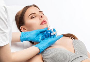 Cosmetologist does injections for lips augmentation and anti wrinkle injections of a beautiful...