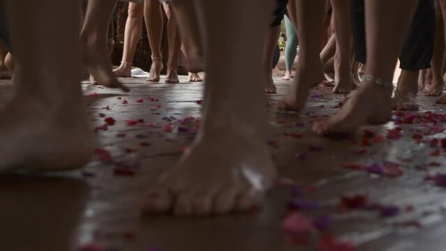 Ecstatic dance, bare feet of dancing people on a wooden floor with flower petals.