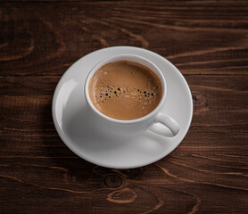 Coffee in a white cup with a saucer on a wooden table