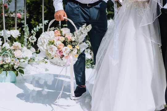 A man invited to the holiday gives a bouquet of flowers in a wicker basket to the bride and groom at the ceremony. Wedding photography, portrait.