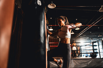 Asian female Muay Thai boxer with strong athletic and muscular body using her knee and fist...
