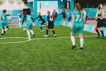 Female football street match outdoor game on an artificial astroturf lawn, girls play soccer game on a pitch field, young women participate in football competition on a stadium with green grass