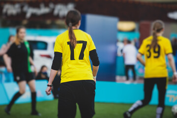 Female football street match outdoor game on an artificial astroturf lawn, girls play soccer game on a pitch field, young women participate in football competition on a stadium with green grass