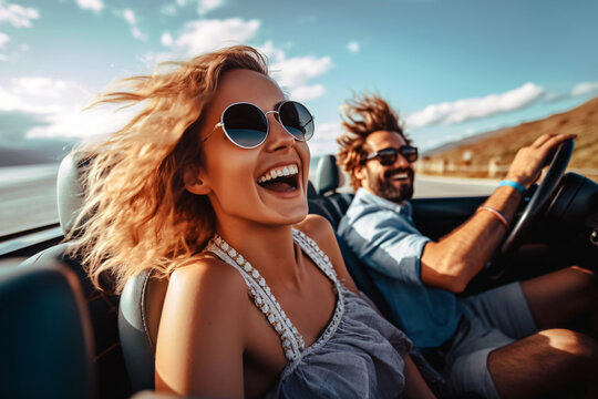 Happy young couple driving in convertible car on road trip. Man and woman laughing and having fun together. Beautiful young woman  with flying hair in the air.
