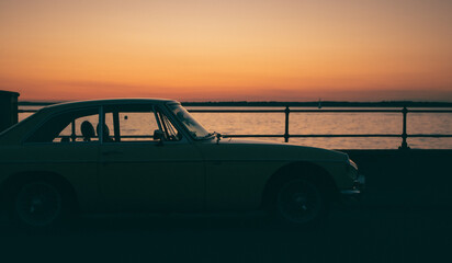 Fototapeta premium A yellow car on the seafront at sunset
