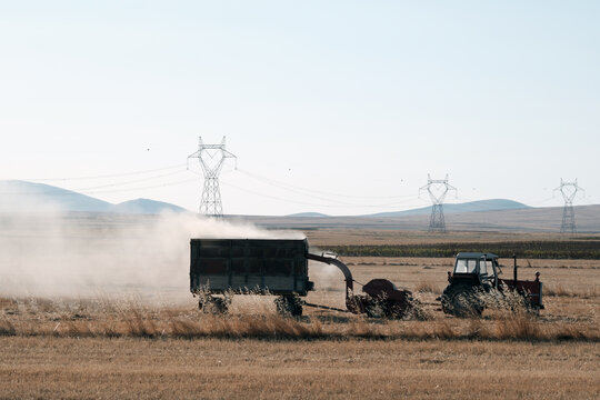 Silhouette of a haymaker working in the field. Harvest machines. 