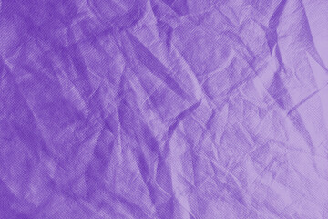 Fototapeta premium Wrinkled, crumpled purple fabric texture background. Wrinkled and creased abstract backdrop of spunbond textile, wallpaper with copy space, top view.