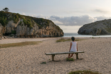Woman sitting on Cuevas del Mar Beach. Council of Llanes, Asturias
