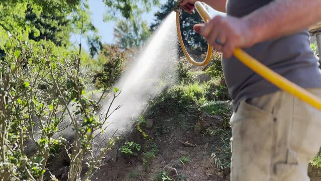 A low angle view of an exterminator spraying termite control chemicals on the hillside in a Pennsylvania home's backyard.  	