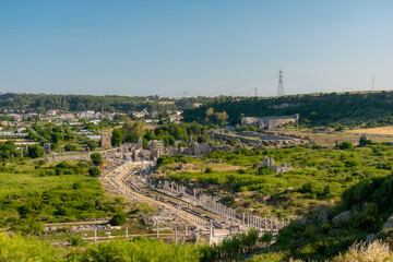 View from a height of the ancient city of Perge. Ancient city surrounded by dense green vegetation.