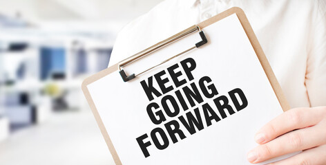 Text KEEP GOING FORWARD on white paper plate in businessman hands in office. Business concept