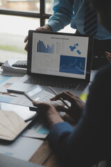 Financial analysts analyze business financial reports on a digital tablet planning investment...