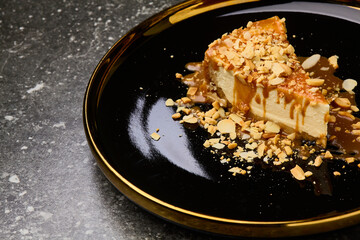 Cheesecake with caramel sauce on black background plate. Tasty caramel cheesecake