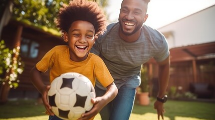 African American father and his son energetically playing football in the backyard.