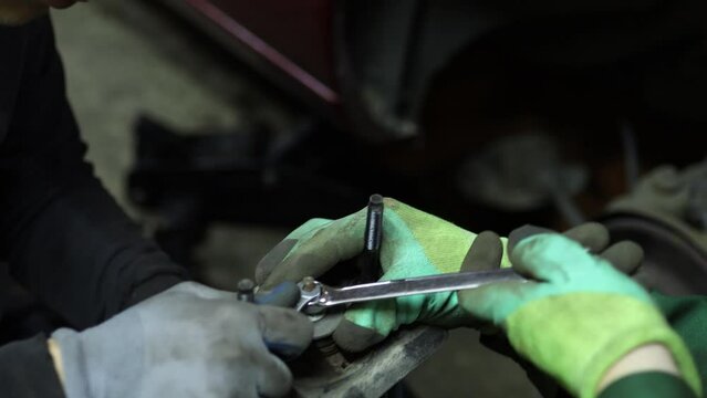 teamwork in a car service center, the hands of two craftsmen tighten the nuts of the shock absorber spring.