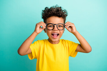 Portrait of impressed small boy with brown hair wear stylish t-shirt fingers touch eyewear laughing...