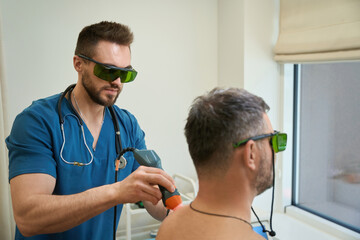 Physical therapist treating patient for backache with medical device