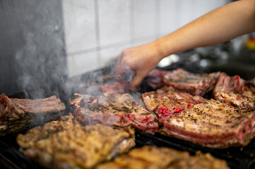 woman chef hand cooking pork ribs on grill in kitchen