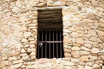 Fototapeta na wymiar Old window in stone wall, metal bar like a prison, ancient ruin Sardinia 