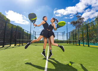 Two padel tennis players with rackets. Woman and girl teenager athlete with paddle racket on court outdoors. Sport concept. Download a high quality photo for the design of a sports app or web site. - 642205812