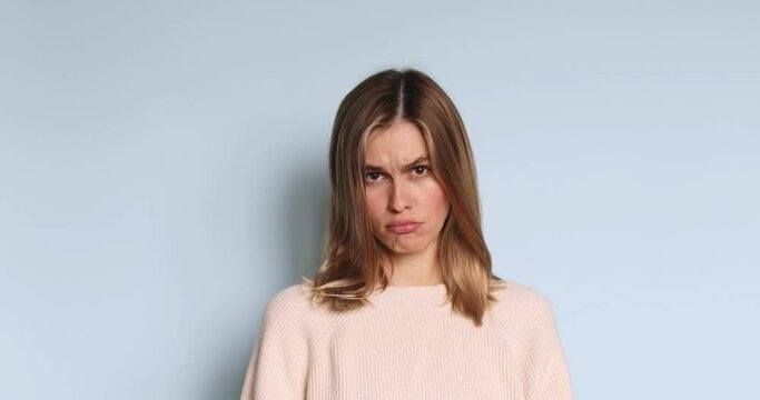 Amazed excited blonde woman in sweater open face in surprise looking at camera with big eyes, shocked. Indoor studio shot isolated on blue background. Oh my god wow! Slow motion.