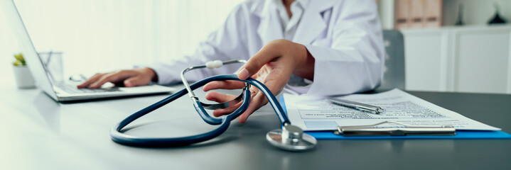 Focus stethoscope on doctor office with blurred background of doctor reviewing medical report and...