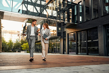 On the way to the office. Full-length shot of two stylish successful full-faced handsome people walking around the business center and discussing the project while gesturing with their hands.