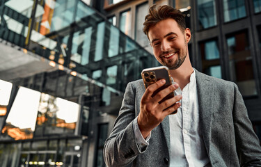 Portrait of attractive confident modern smiling happy adult dressed gray suit man holding a phone...