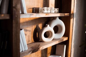 Modern beige and white home decor and books on a shelf. Wooden shelf. Banner with copy space.