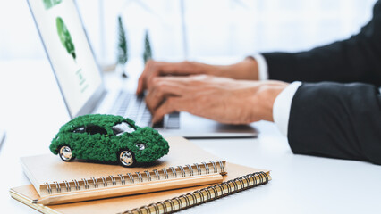 Businessman working in office developing plan or business project on eco-friendly ev car using net...