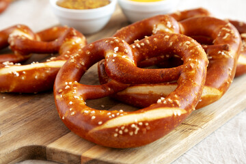 Homemade Soft Bavarian Pretzels with Mustard on a wooden board, side view.