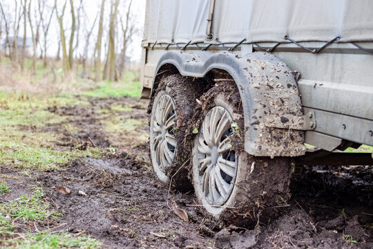 Car two-axle trailer with wheels covered with mud on a muddy road in autumn. Transportation of goods on a bad road