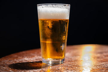 Pint glass of cold fresh british ale and lager beer served in old vintage English pub