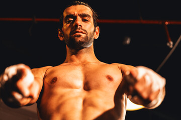 Fototapeta na wymiar Boxing fighter shirtless posing, caucasian boxer punch his bare fist and wrap in front of camera, aggressive stance and ready to fight at the boxing ring. Impetus