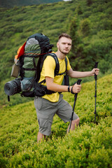 a stylish traveler in yellow tourist clothes goes along a tourist mountain route in the Carpathian Mountains of Ukraine