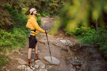 a stylish traveler in yellow tourist clothes goes along a tourist mountain route in the Carpathian...