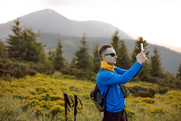the traveler takes a photo on the phone against the background of mountain landscapes. A tourist is...