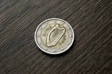 Used coin on a dark wooden table. Irish 2 euro coin.