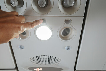 A hand of a passanger adjusting the cabin light inside a commercial plane