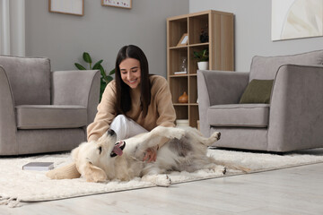 Happy woman playing with cute Labrador Retriever dog on floor at home. Adorable pet